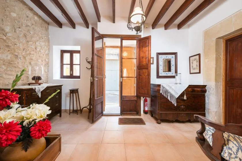 A bright entry hall with an open wooden doorway and a flower arrangement.