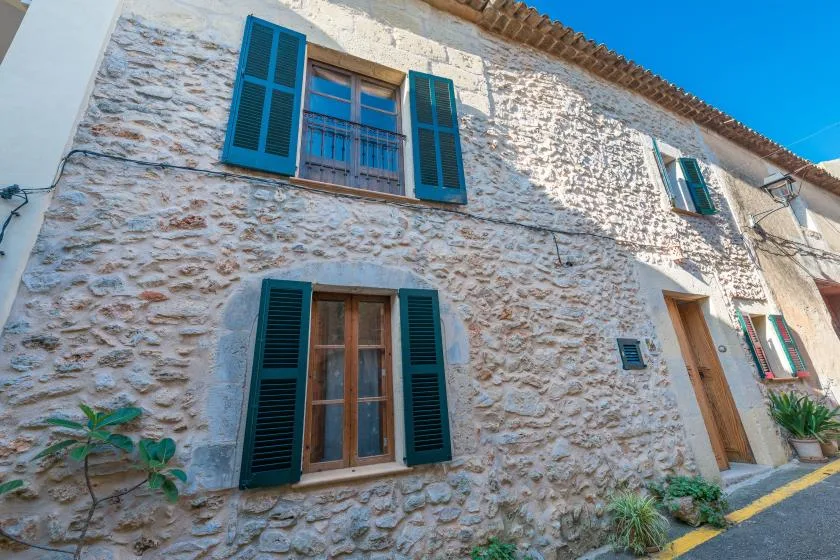 A stone building facade with shuttered windows and a wooden entrance door.