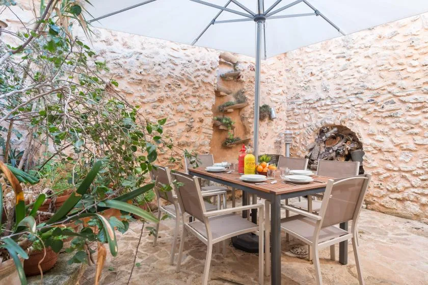 An outdoor dining area with a table and chairs beneath a large umbrella.