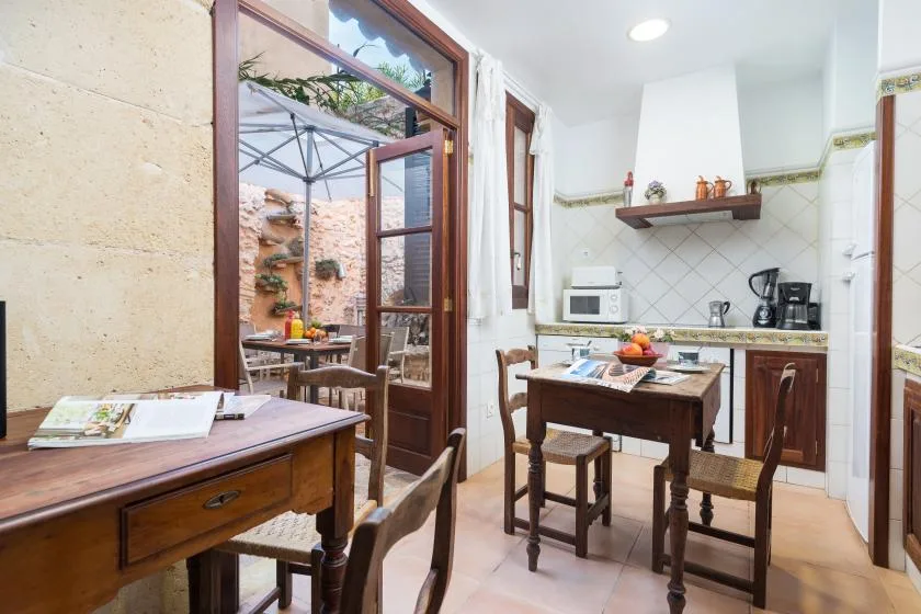 A dining area with wooden tables beside an open doorway to a patio.