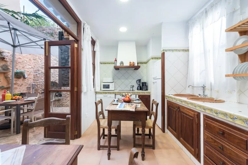 Una cocina luminosa con comedor, gabinetes de madera y una mesa.