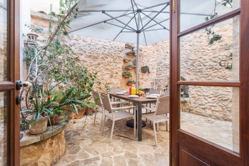 A stone-paved patio with a dining table beneath a large umbrella.