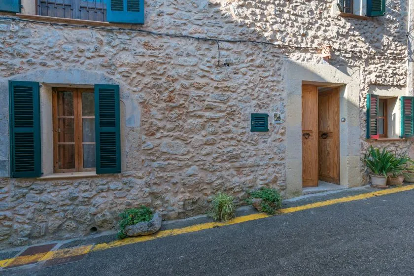 A stone building facade with shuttered windows and a wooden entrance door.