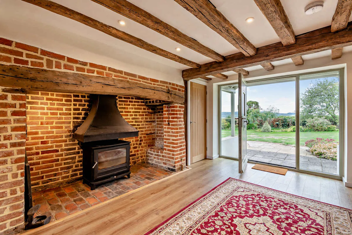 A living room with a brick fireplace and large glass doors opening onto a garden.