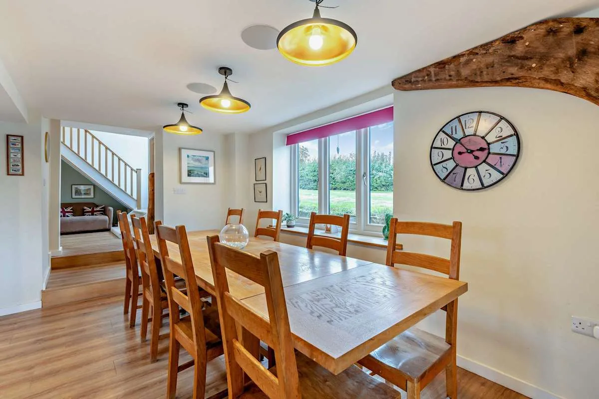 A dining area with a long wooden table and large windows.