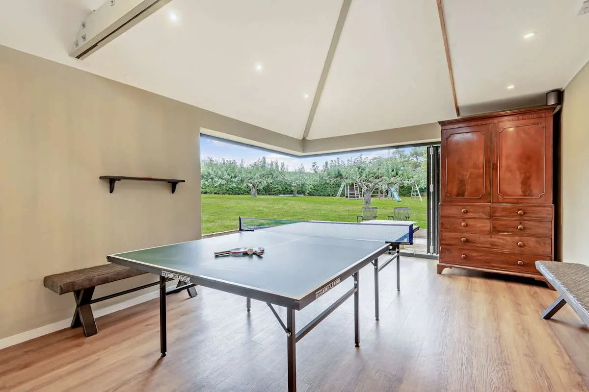 A table tennis room opens onto a lawn through wide windows.