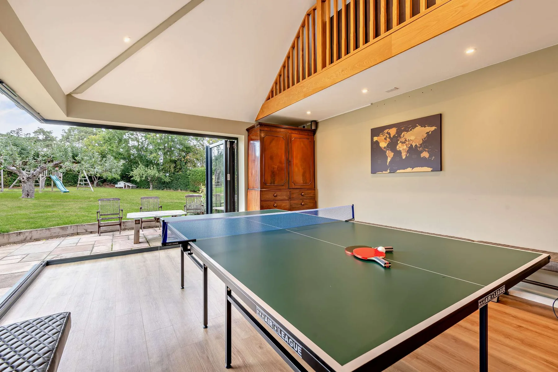 A game room with a ping-pong table beside open doors to the garden.