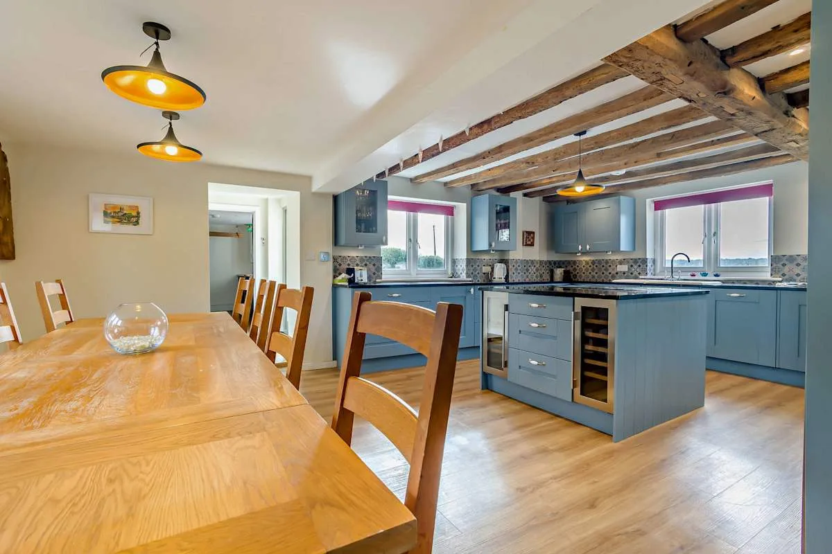 A kitchen and dining area with blue cabinets and a wooden dining table.