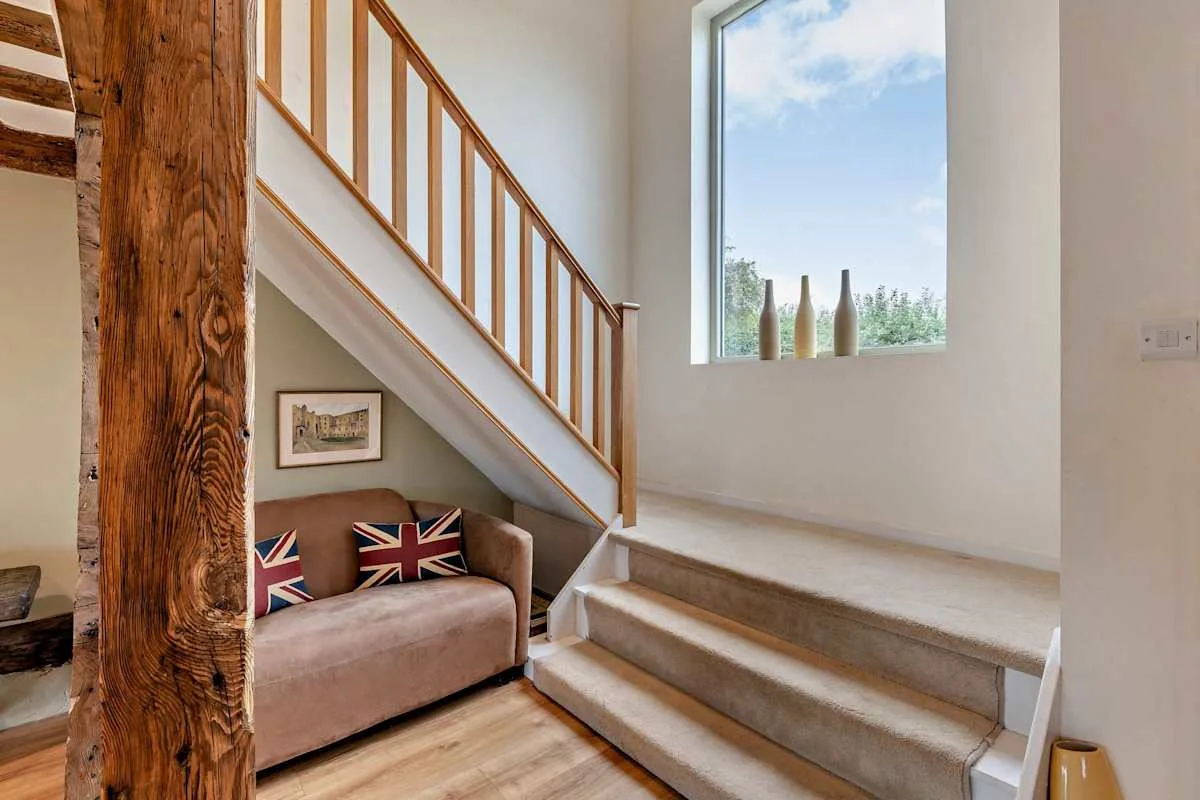 A stairway beside a small seating area and a large window.