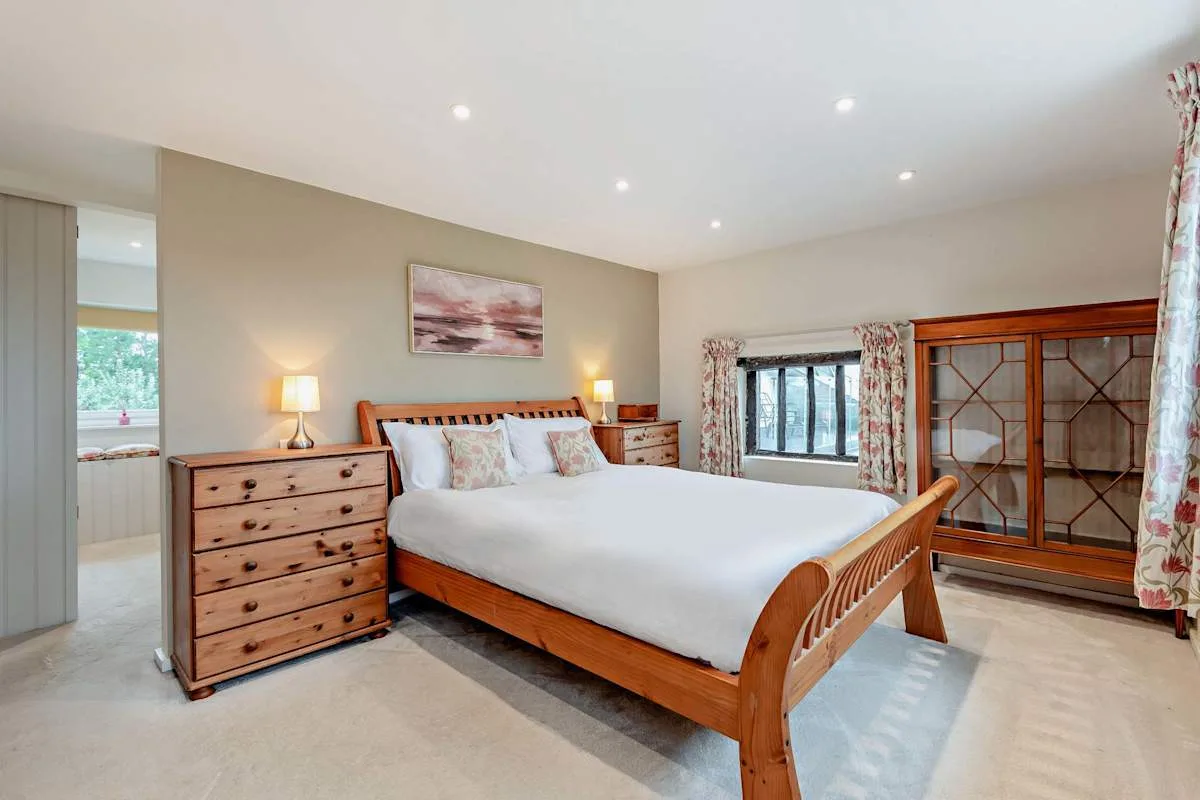 A bedroom with a wooden bed, matching bedside lamps, and a dresser.