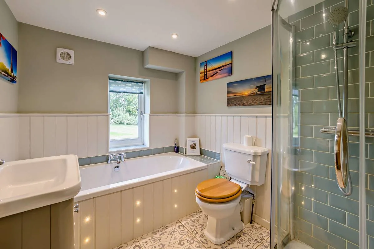 A bathroom with a bathtub, toilet, and glass-enclosed shower.