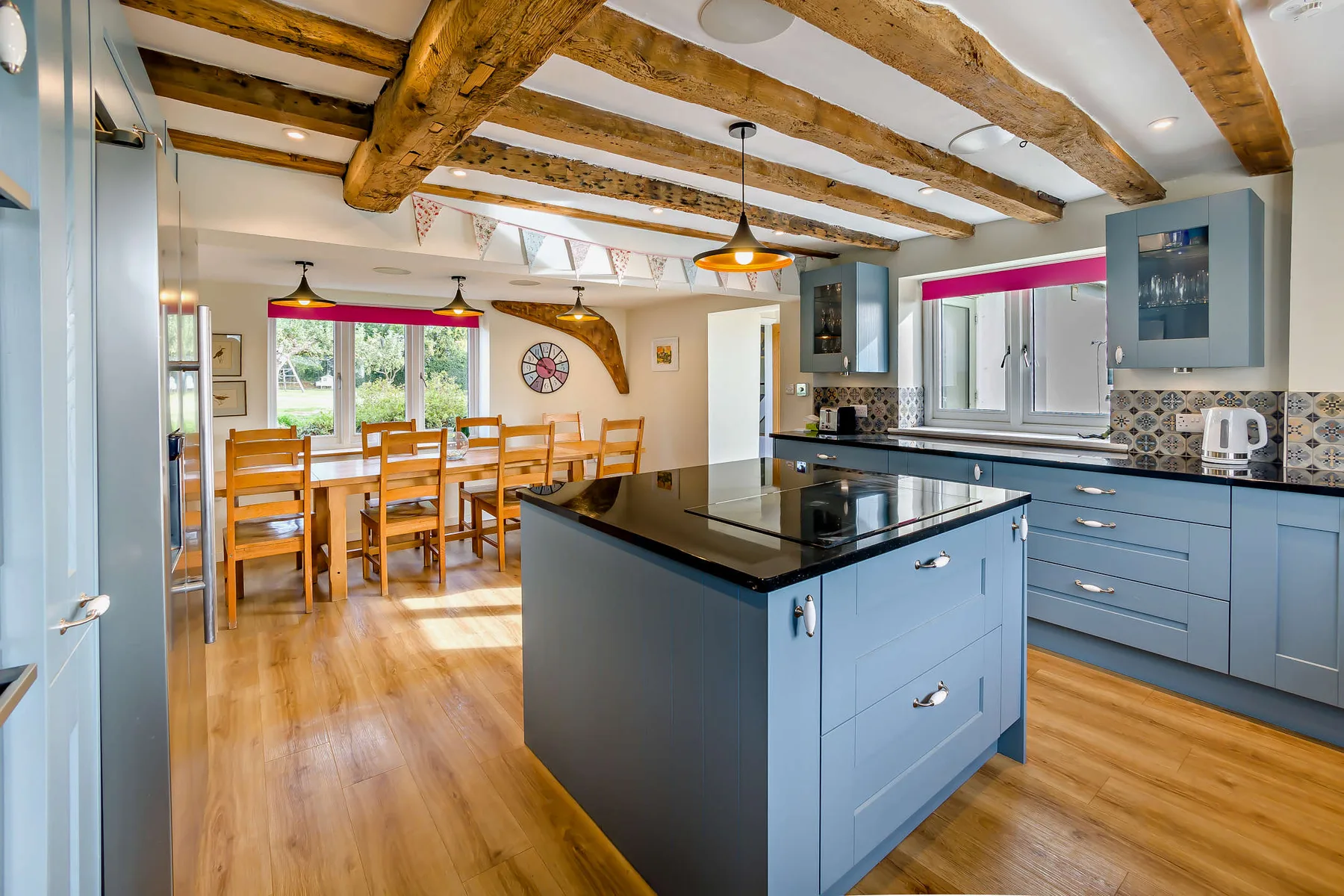 Una cocina amplia con una isla central y una mesa de comedor de madera junto a las ventanas.