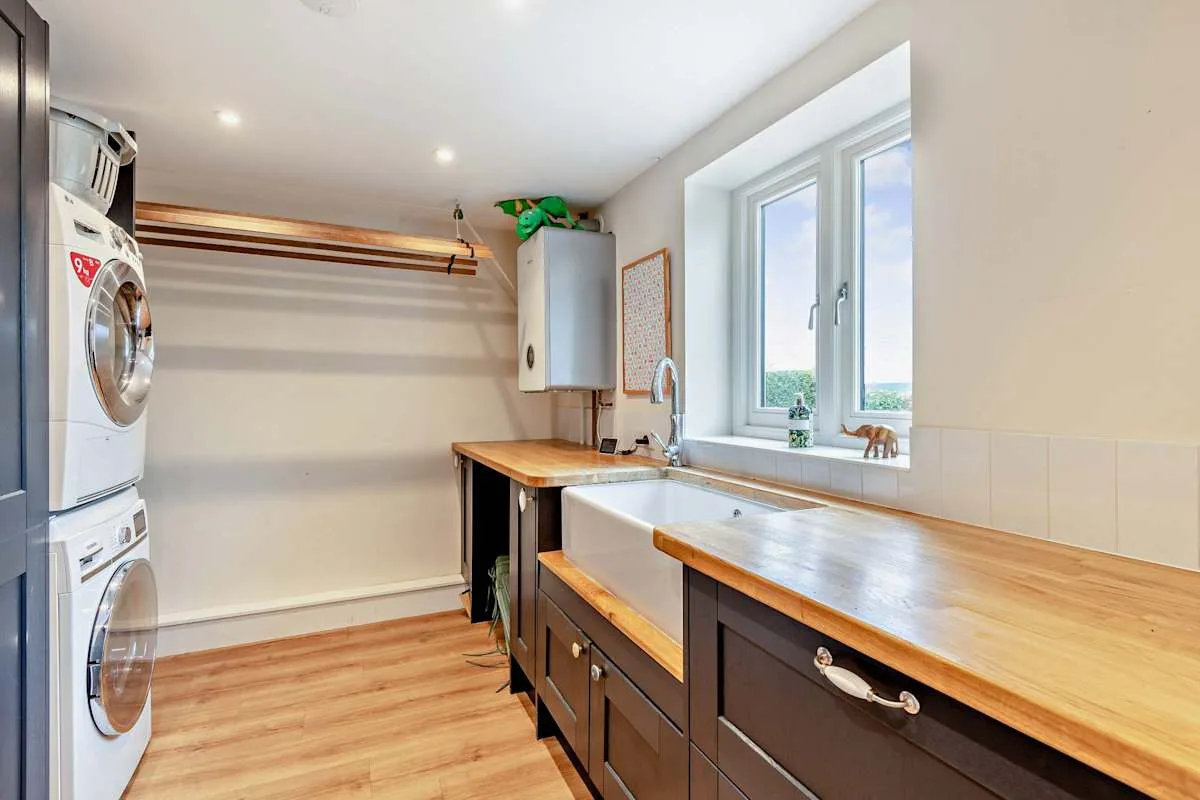 A laundry room with washing machines, wooden counters, and a large sink.