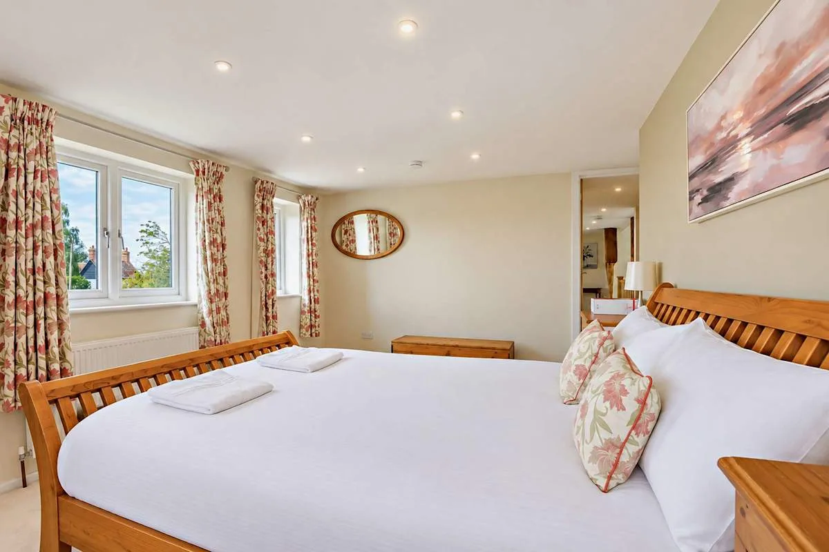 A bedroom with a large bed, floral curtains, and a window.