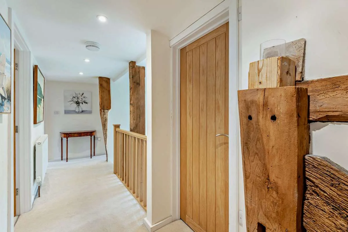 A bright hallway with a wooden door and a railing along the stairs.
