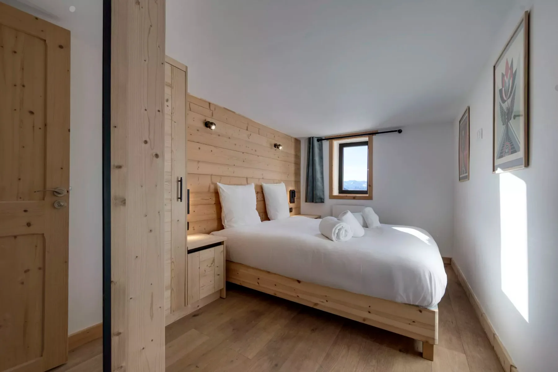 Un dormitorio luminoso con una cama bien tendida y una pared revestida de madera.