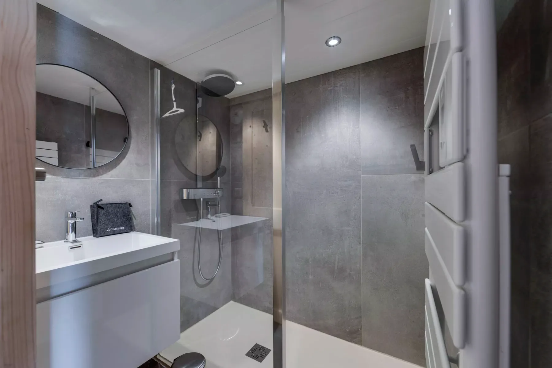Un baño moderno con ducha de cristal y lavabo suspendido.