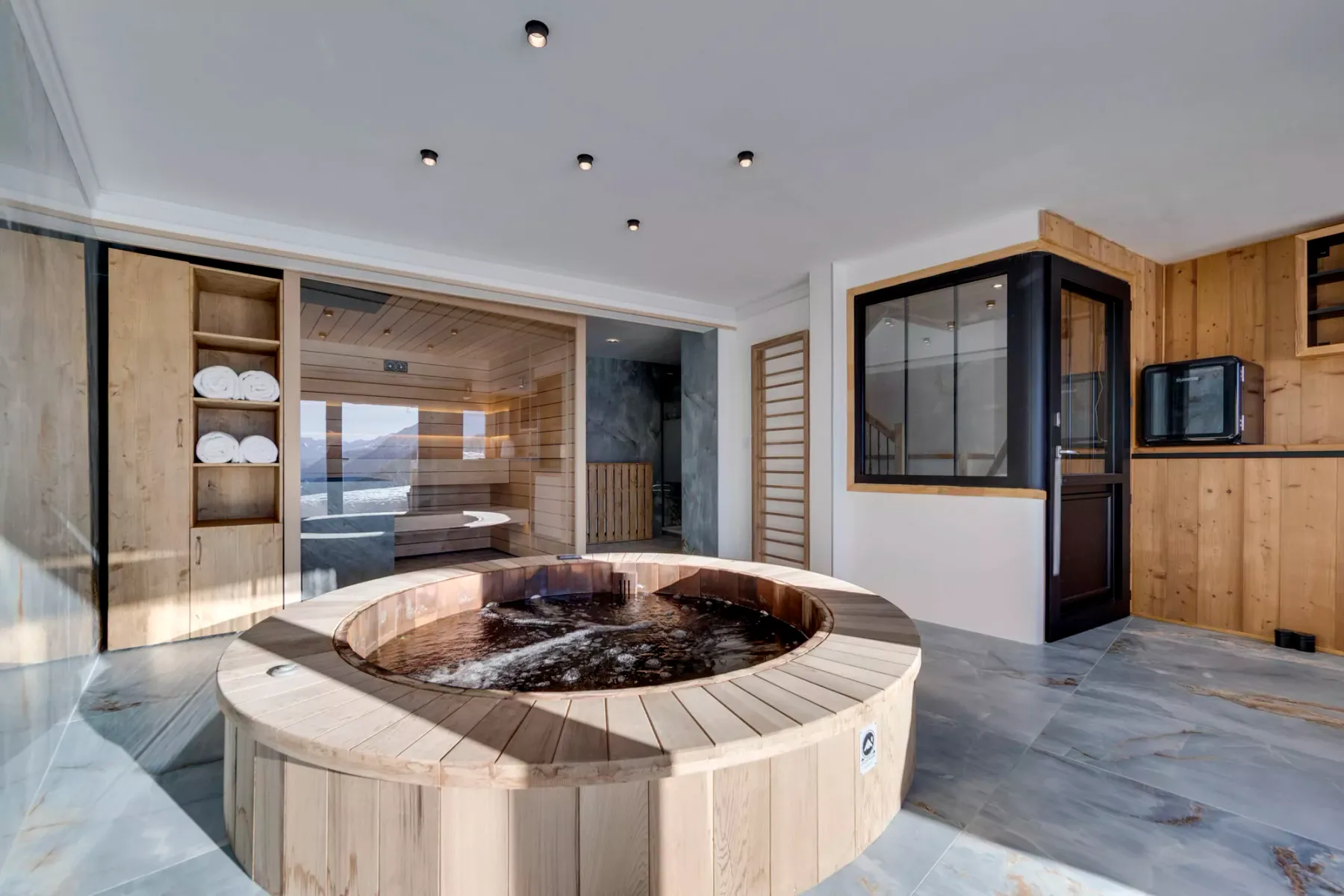 A circular hot tub sits in a wood-paneled spa room.