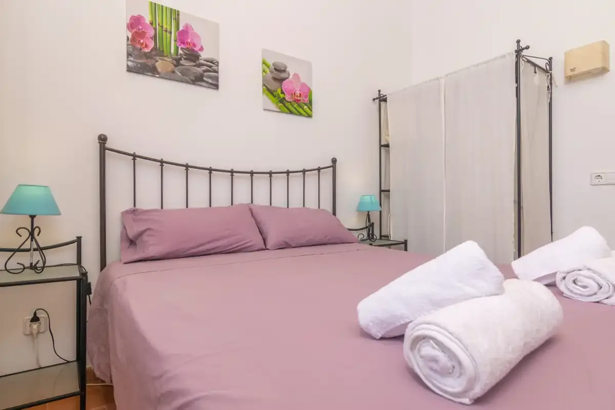 Un dormitorio con una cama vestida con ropa de cama rosa y toallas blancas dobladas.