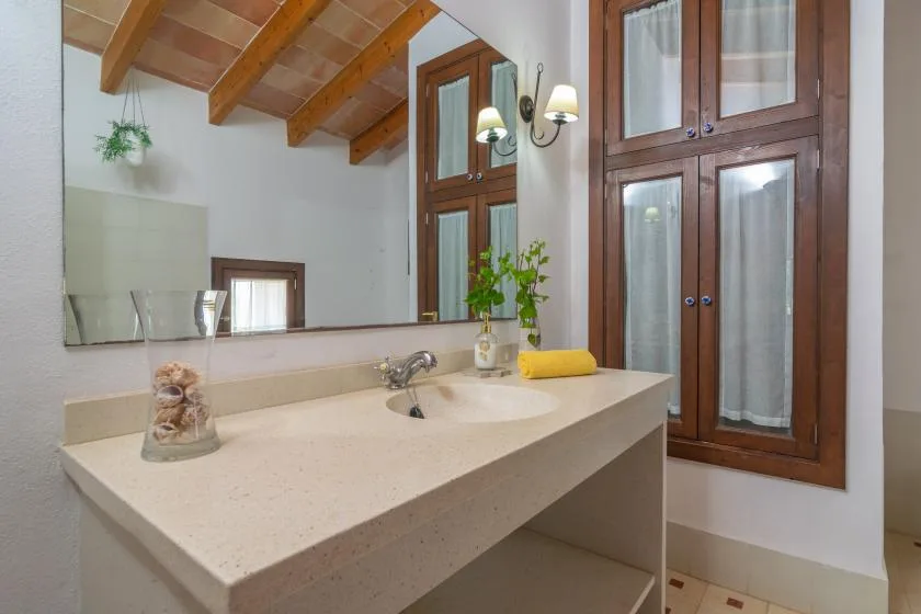 Un tocador de baño con una amplia encimera está bajo un techo inclinado de madera.