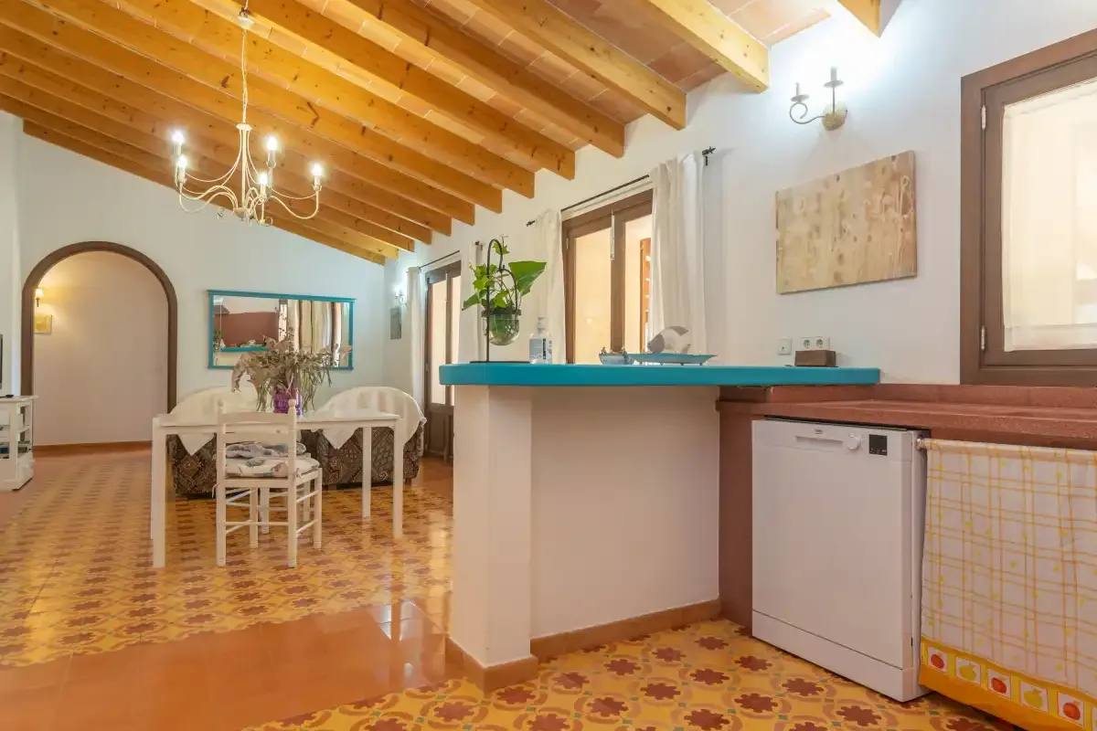 Una cocina y comedor con una encimera turquesa y vigas de madera en el techo.