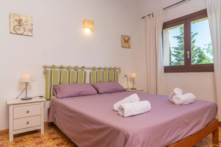 Un dormitorio con una cama malva, un cabecero a rayas y una ventana.