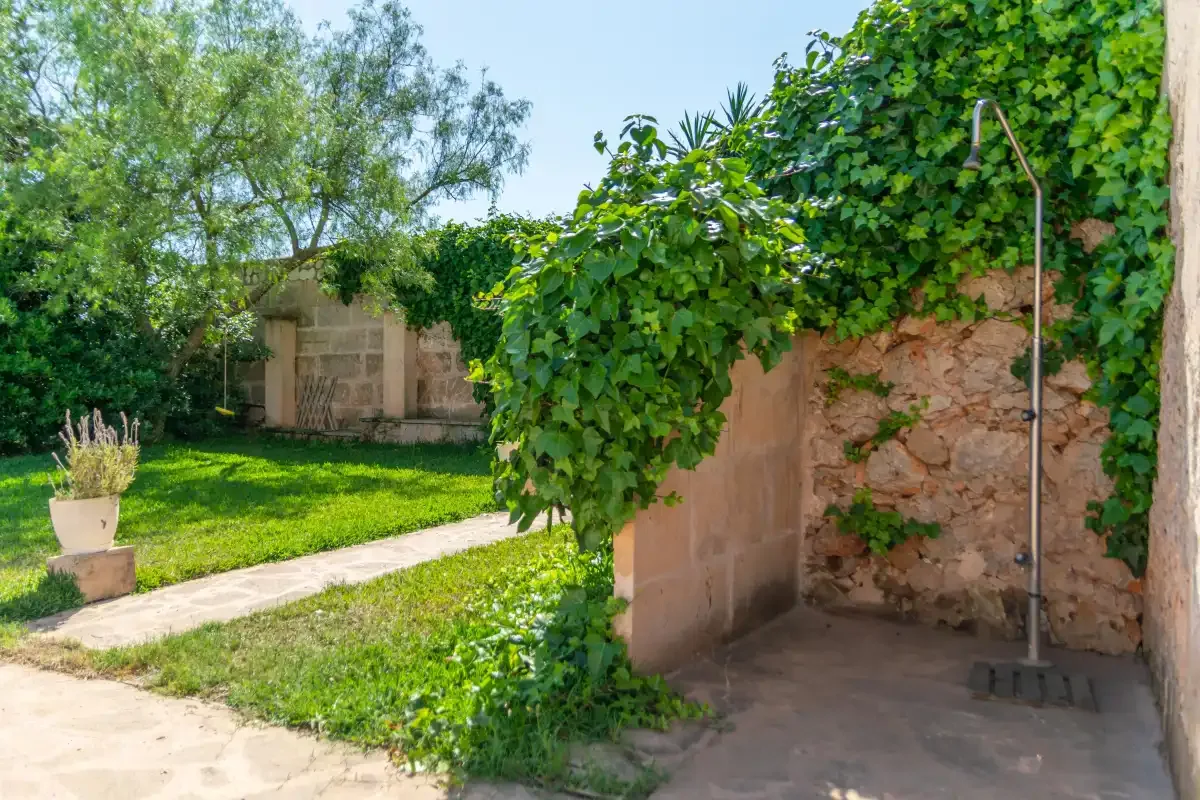 Un patio ajardinado con un muro de piedra y un sendero pavimentado.