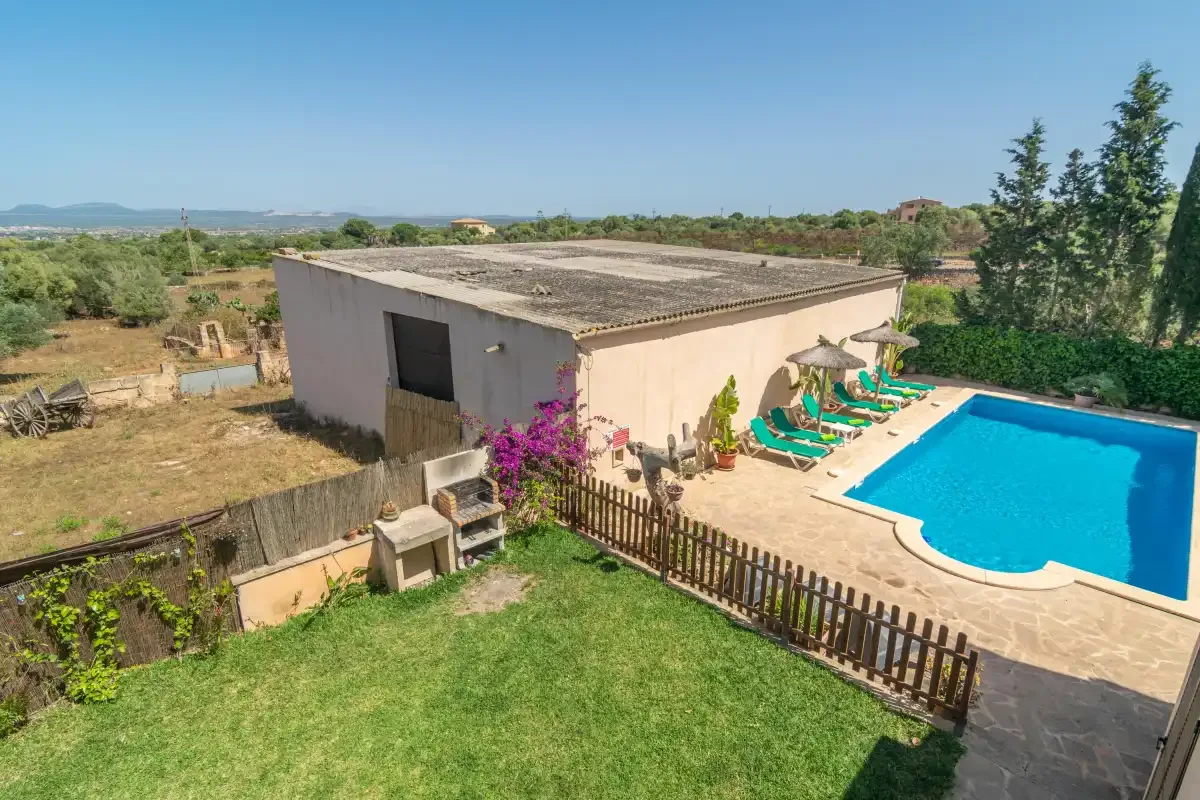 Un edificio de una planta junto a una piscina y un jardín.