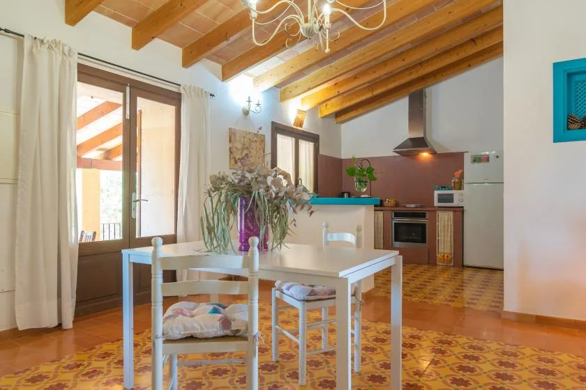 Un comedor se abre a una cocina bajo vigas de madera expuestas.