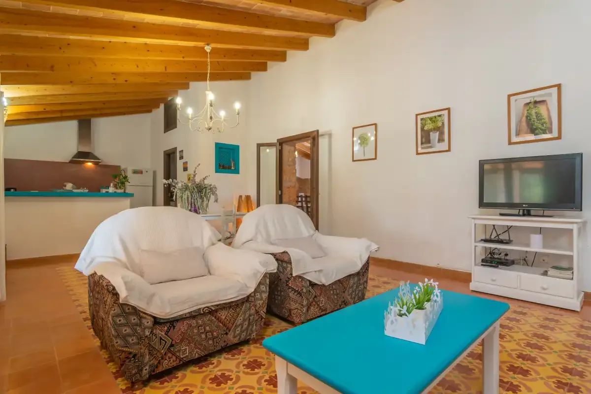 Una sala de estar con asientos cubiertos, una mesa de centro turquesa y un televisor.