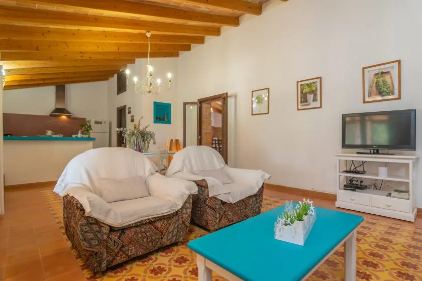 Una sala de estar con asientos acolchados, un televisor y una mesa de centro azul brillante.