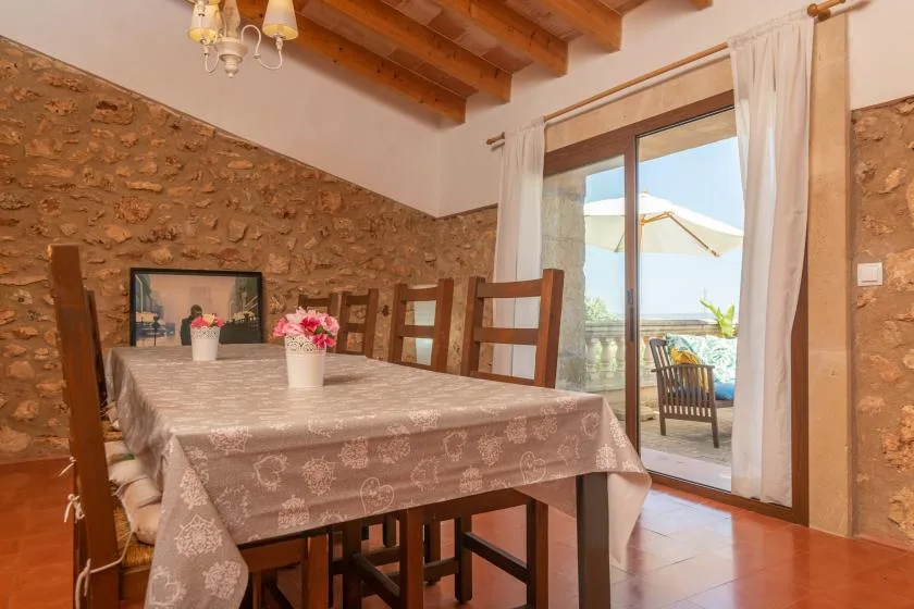 Comedor con una mesa de madera junto a puertas de vidrio que dan a una terraza.