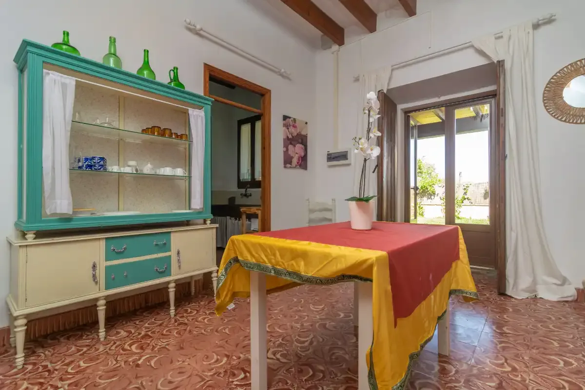 Un comedor con un mantel colorido y un armario con puertas de cristal.