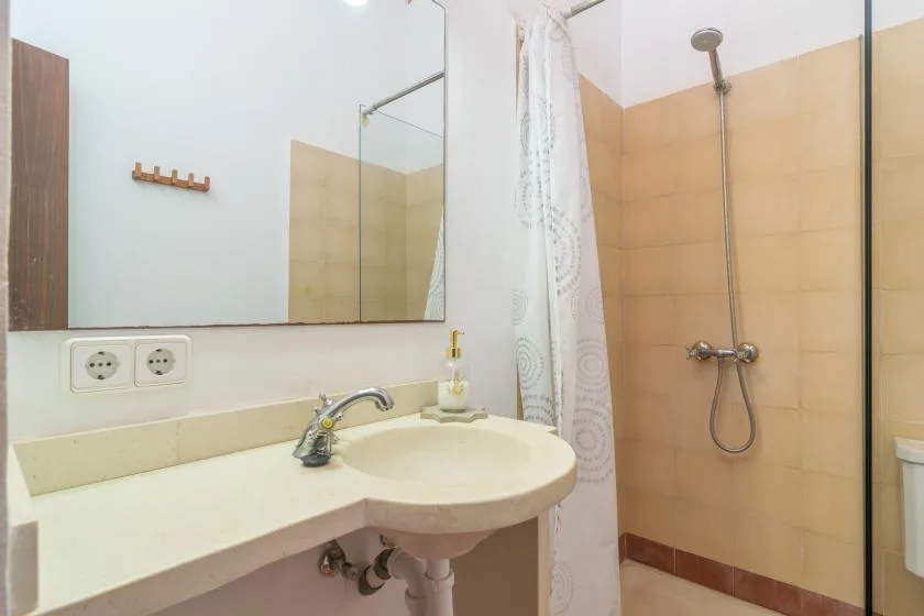Un baño con lavabo y una ducha detrás de una cortina.