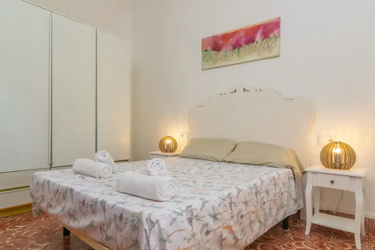 Un dormitorio con una cama doble, mesitas de noche y lámparas cálidas.