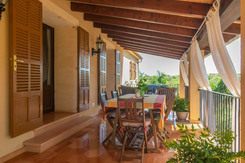 Una zona de comedor exterior cubierta con mesa, sillas y plantas.