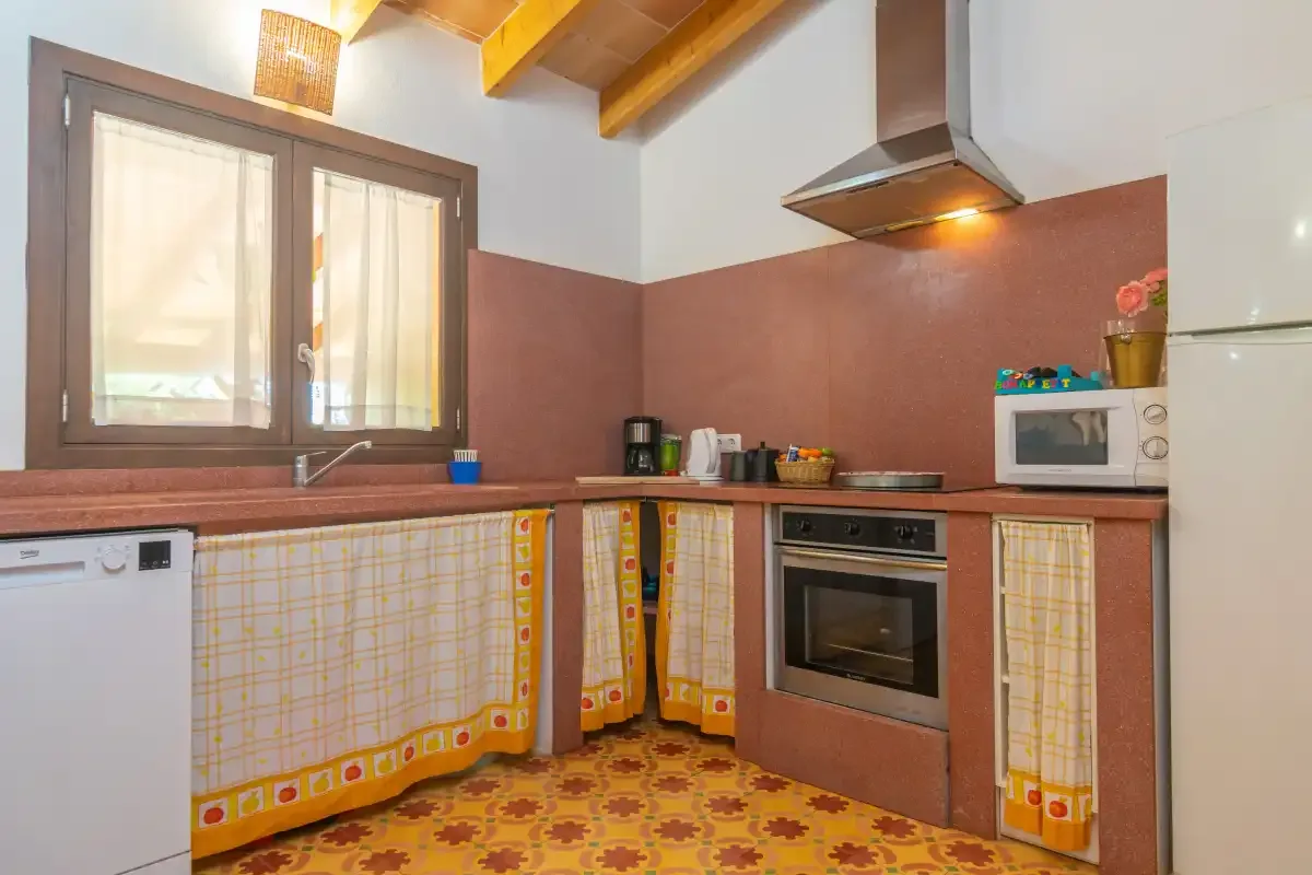 Una cocina con vigas de madera en el techo y suelo de baldosas estampadas.