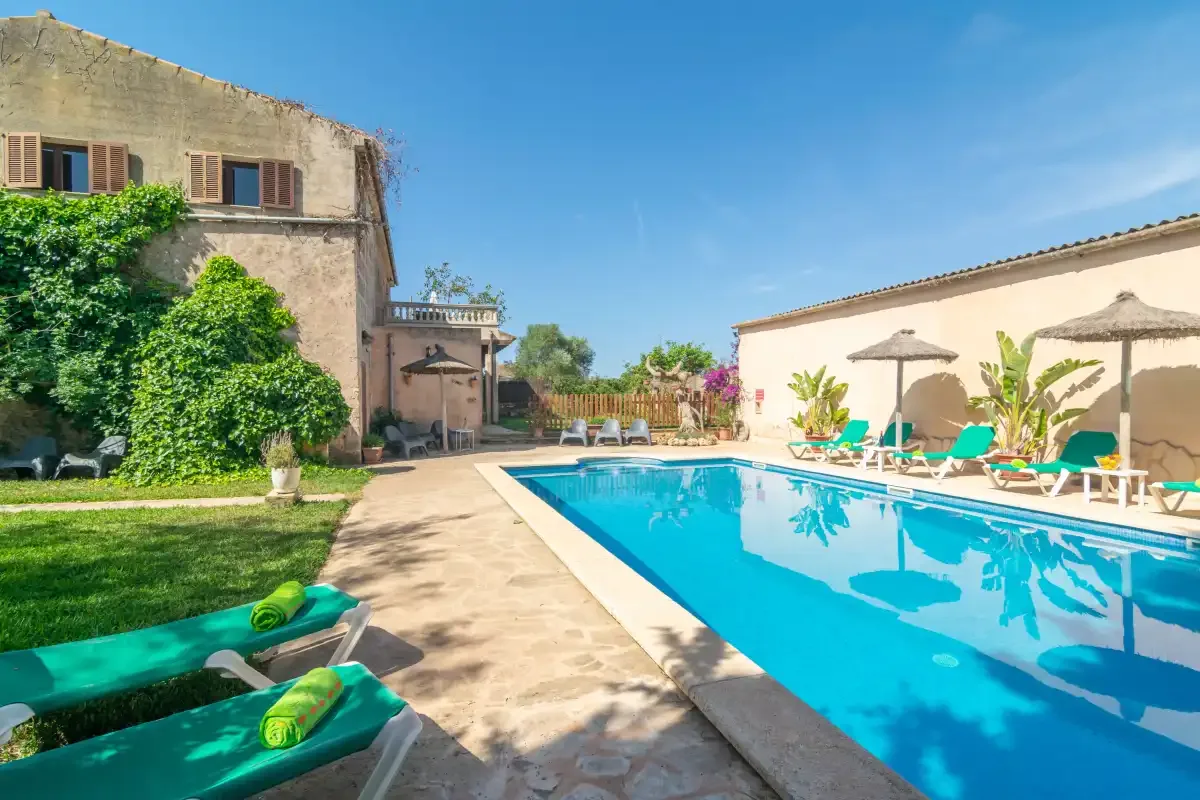 Una piscina junto a un patio soleado con asientos reclinables.