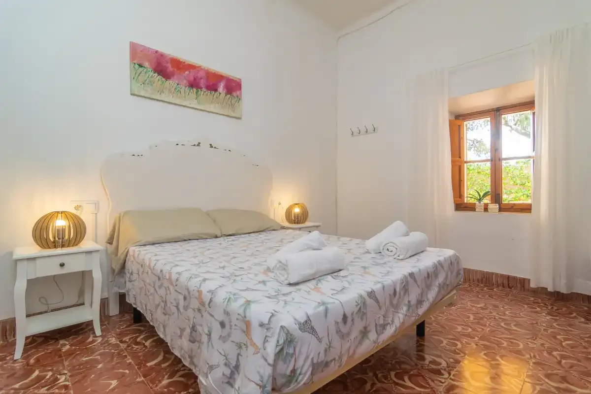 Un dormitorio con una cama doble, mesitas de noche y una ventana.