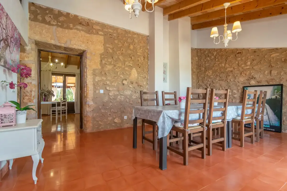 Comedor con una mesa larga y asientos de madera junto a paredes de piedra vista.