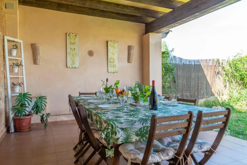 Un comedor exterior cubierto con una mesa larga y asientos de madera.