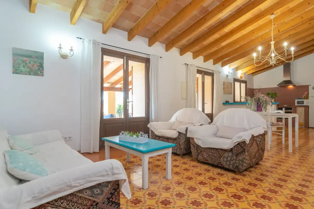 Una sala de estar con asientos, una mesa de centro turquesa y vigas de madera a la vista.