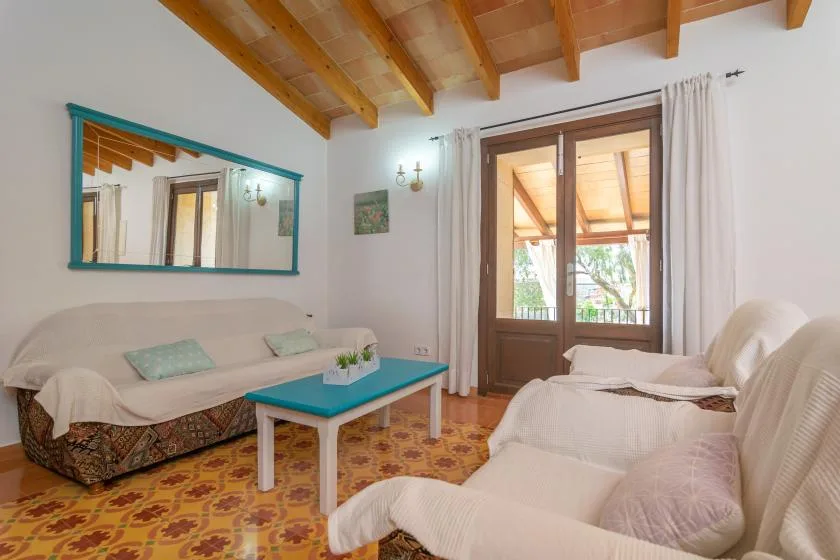Una sala de estar con asientos, una mesa de centro turquesa y un techo con vigas de madera.