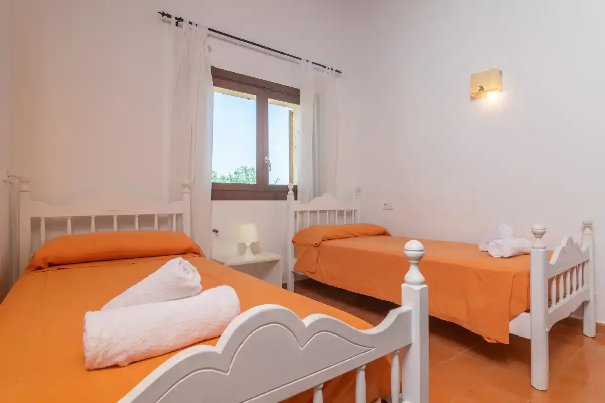 Un dormitorio con dos camas vestidas con ropa naranja y una ventana.