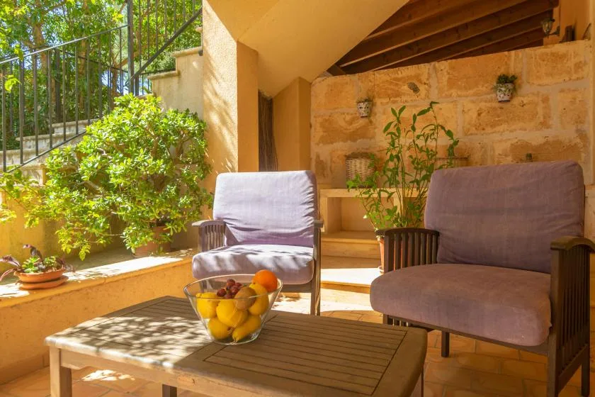 Un patio soleado con dos asientos acolchados y una mesa baja.