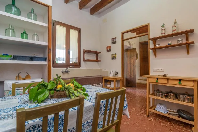 Una cocina con comedor, mesa, estantes de madera y vigas a la vista.