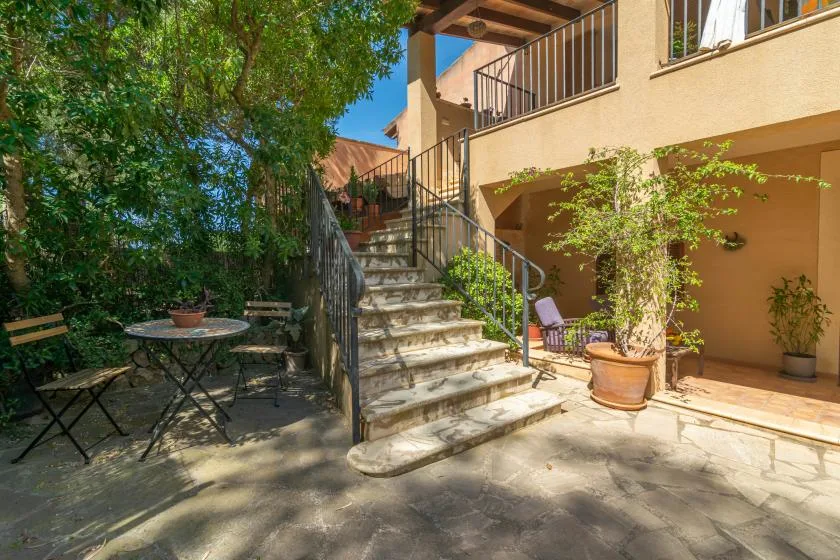 Un patio pavimentado con asientos al aire libre y una escalera junto a un edificio.