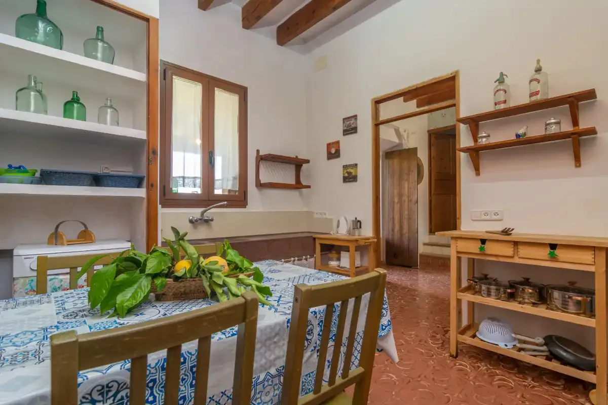 Un comedor con una mesa cubierta con un mantel azul estampado y sillas de madera.