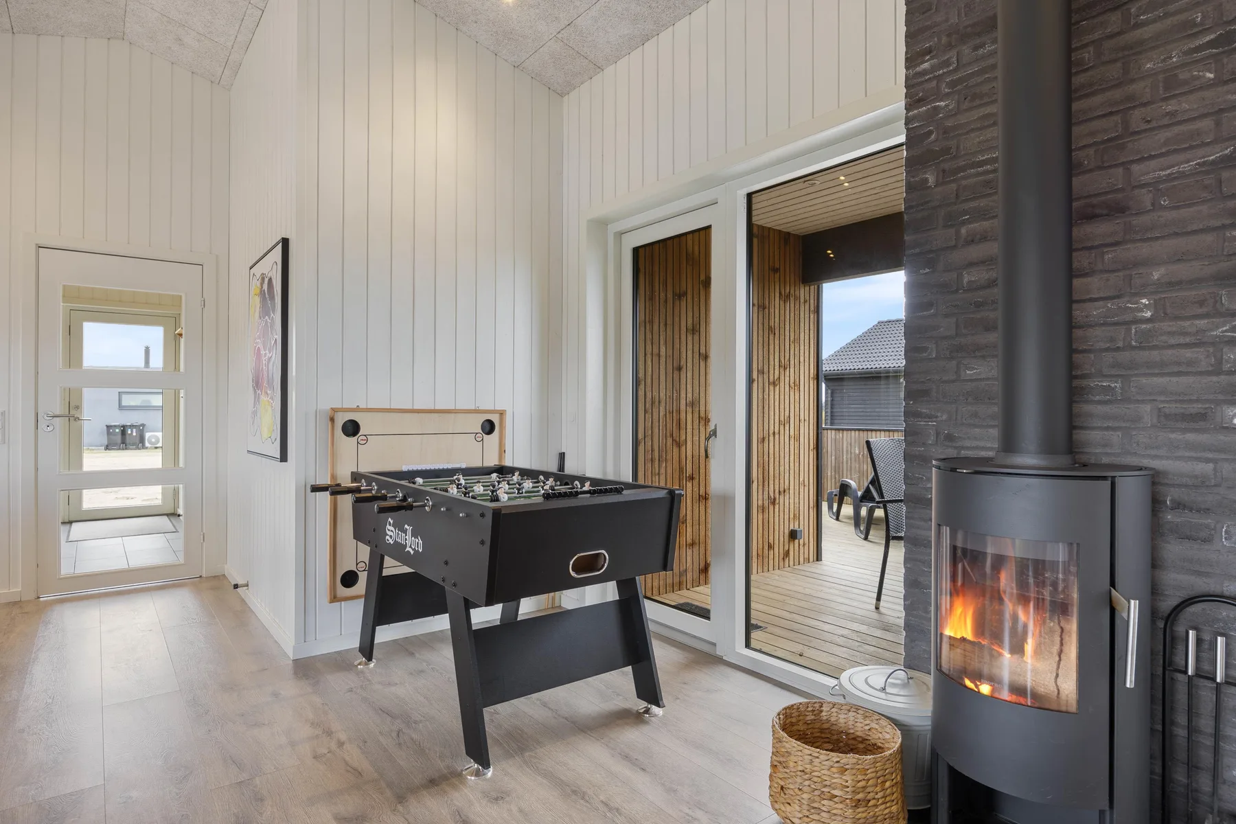 A bright game room features a foosball table beside a lit wood stove.
