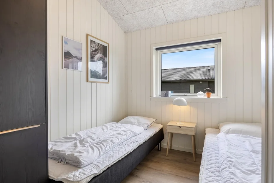 A bedroom with two single beds and a small table beneath the window.